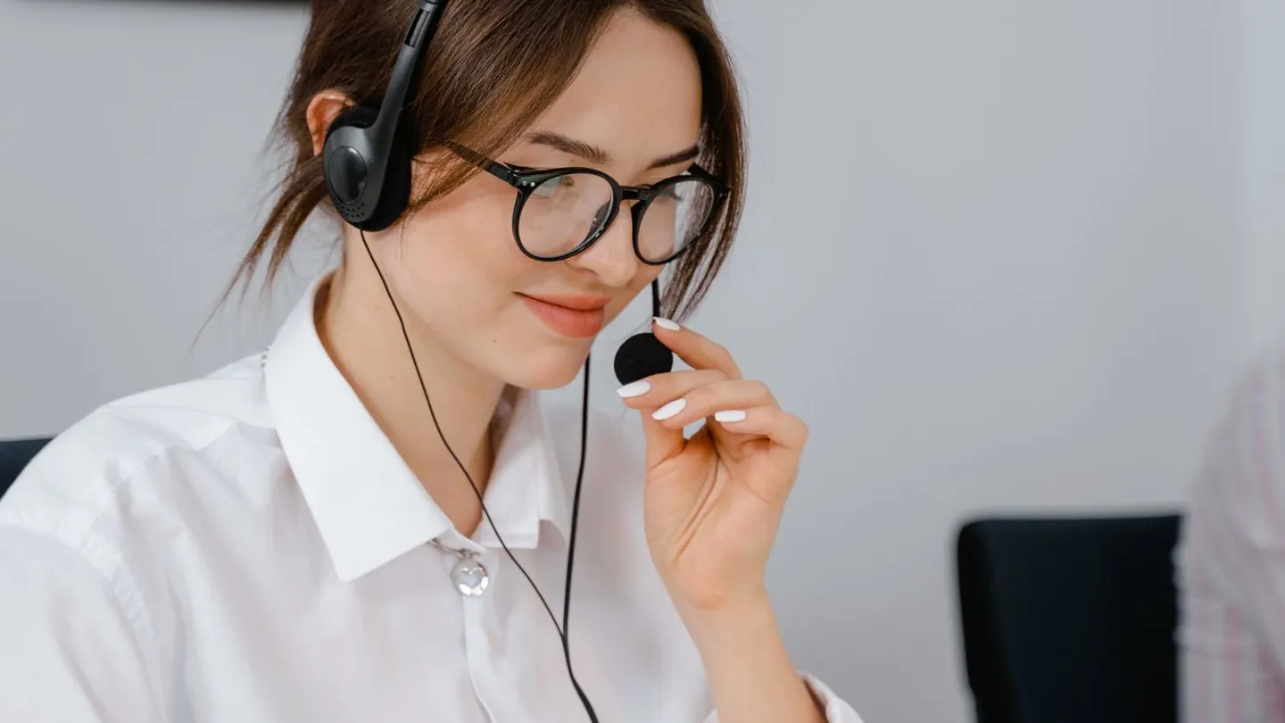 Customer support operator wearing a headset while handling missed-call follow-up from a laptop.
